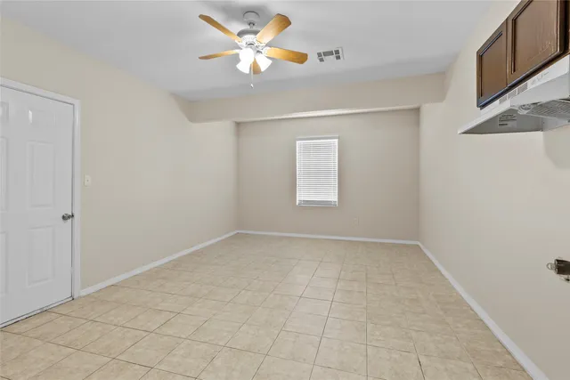 an empty room with a chandelier fan and windows