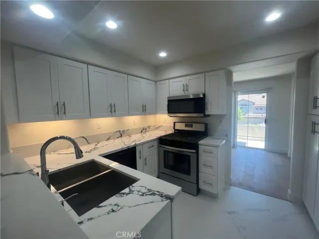 a kitchen with kitchen island stainless steel appliances a sink stove and refrigerator