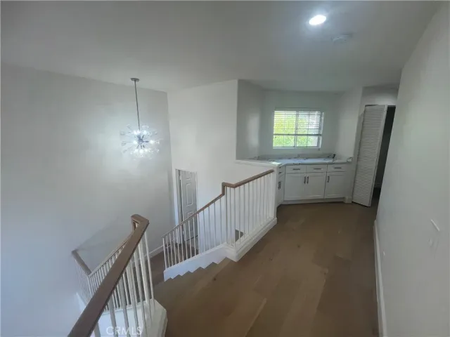a view of hallway with window and wooden floor