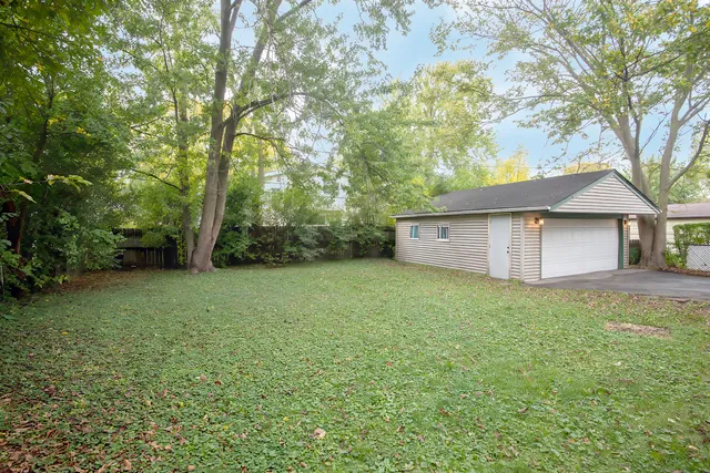 a view of a backyard with large trees and wooden fence