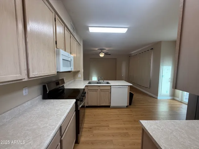a kitchen with granite countertop wooden floors appliances and cabinets