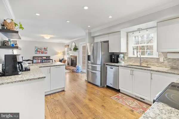 a kitchen with stainless steel appliances granite countertop a refrigerator a stove a microwave oven a dining table and chairs with wooden floor