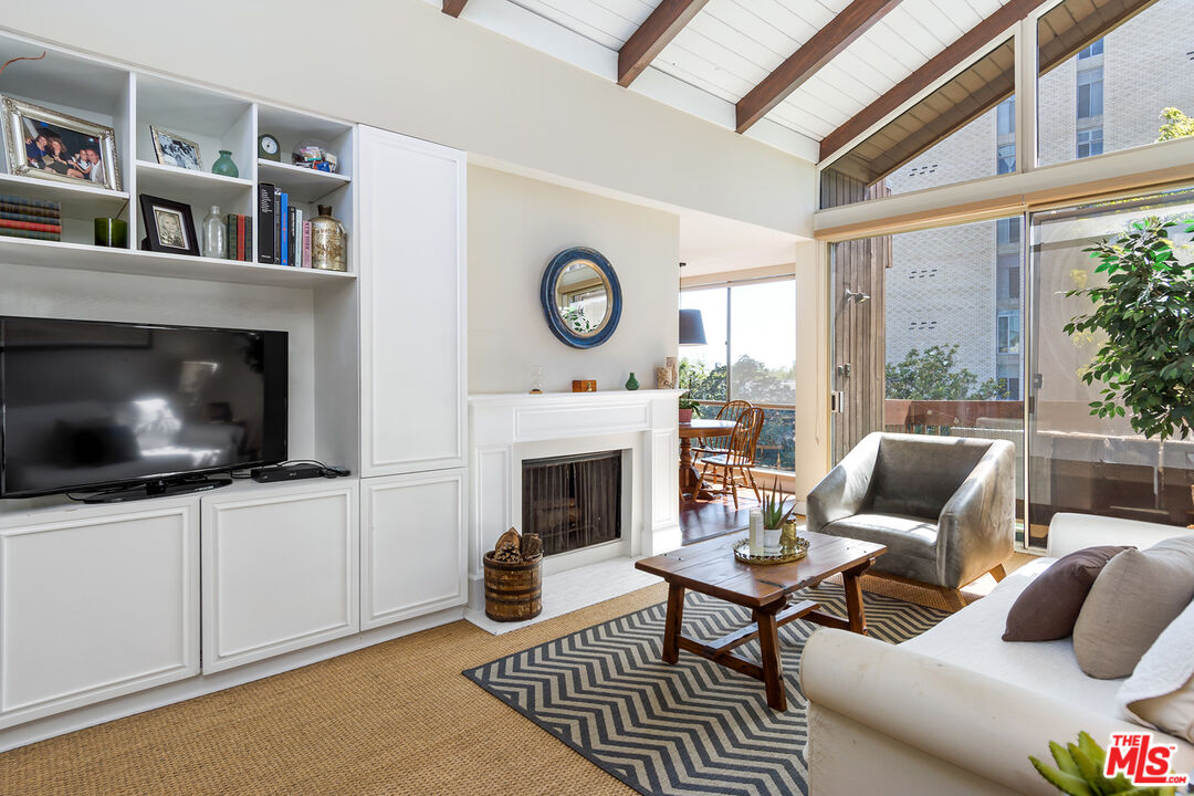 1340 South Beverly Glen Boulevard, Unit 307 Los Angeles, CA 90024 - Photo 2 of 18 a living room with furniture a fireplace and a floor to ceiling window