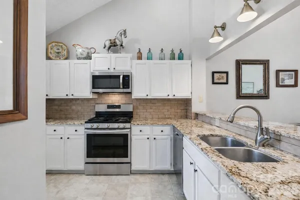 a kitchen with granite countertop a sink stove and cabinets