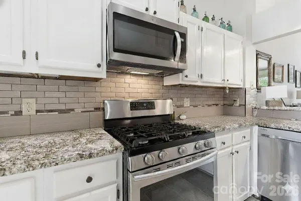 a kitchen with stainless steel appliances granite countertop white cabinets and stove