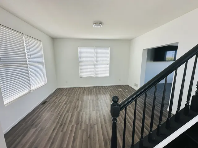 a view of an empty room with wooden floor and stairs