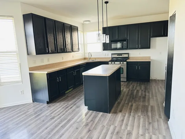 a kitchen with stainless steel appliances granite countertop wooden cabinets a refrigerator and a sink