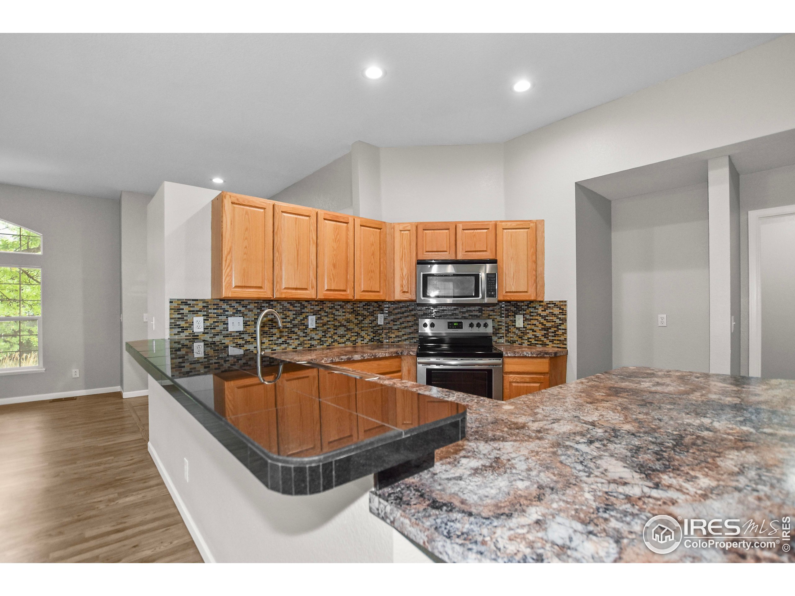 1680 Foxbrook Way Fort Collins, CO 80526 - Photo 23 of 42 a kitchen with stainless steel appliances kitchen island granite countertop a sink and a wooden floor