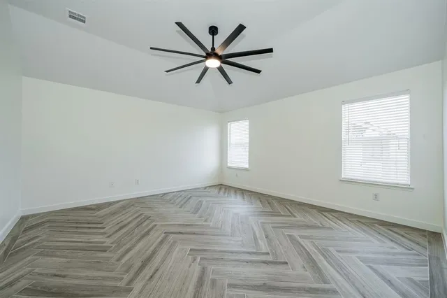 a view of empty room with window and ceiling fan