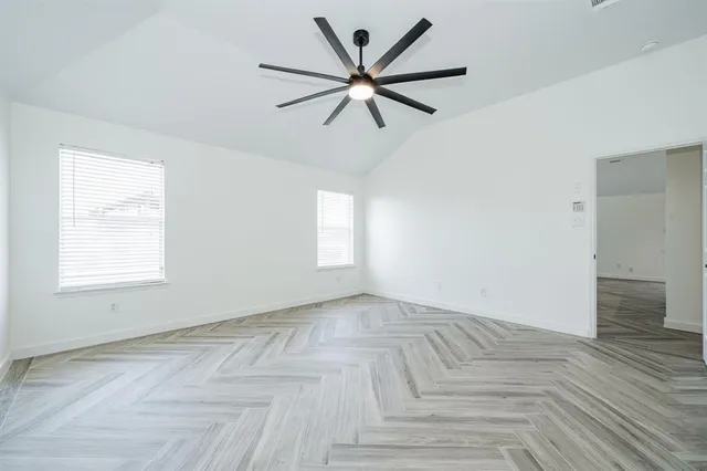 a view of empty room with wooden floor and fan
