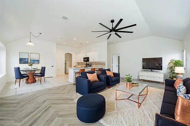 a living room with furniture a ceiling fan and a flat screen tv