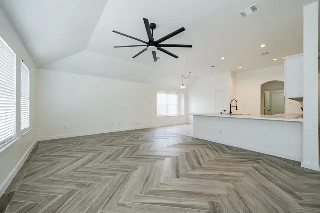 a view of an empty room with window and wooden floor