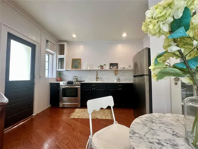 a kitchen with stainless steel appliances kitchen island granite countertop a refrigerator a sink a stove and a wooden floors