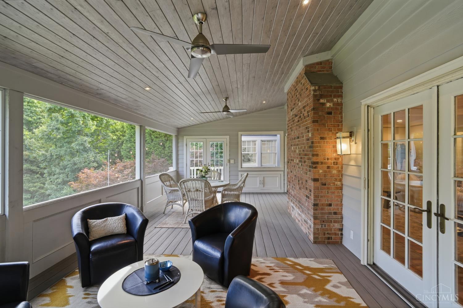 2780 Walsh Road Cincinnati, OH 45208 - Photo 8 of 77 The serene screened porch just off the family room offers the perfect extension of living space—featuring low-maintenance composite decking, a vaulted wood ceiling with ceiling fans and a striking brick accent wall. Designed for both dining and lounging, this inviting retreat is surrounded by lush, tree-lined views, creating a peaceful setting for relaxing or entertaining in every season.