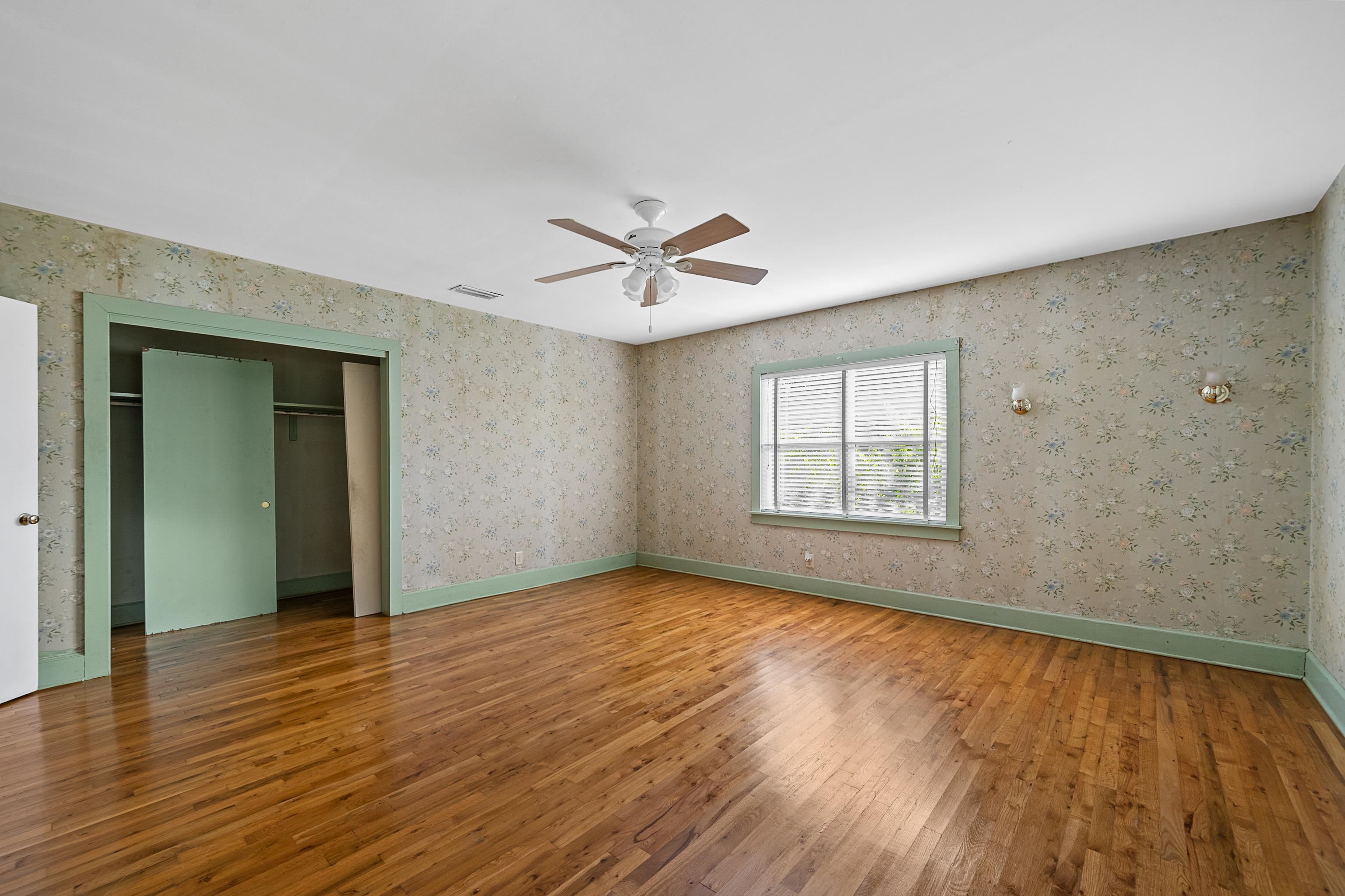 9350 Tompkins Road Stockton, AL 36579 - Photo 17 of 36 Unfurnished bedroom featuring hardwood / wood-style floors, a closet, ceiling fan, and wallpapered walls