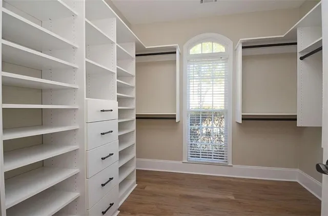 a view of an empty room with a window and wooden floor
