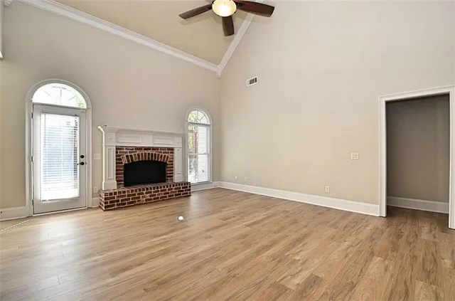 an empty room with wooden floor a fireplace and a chandelier