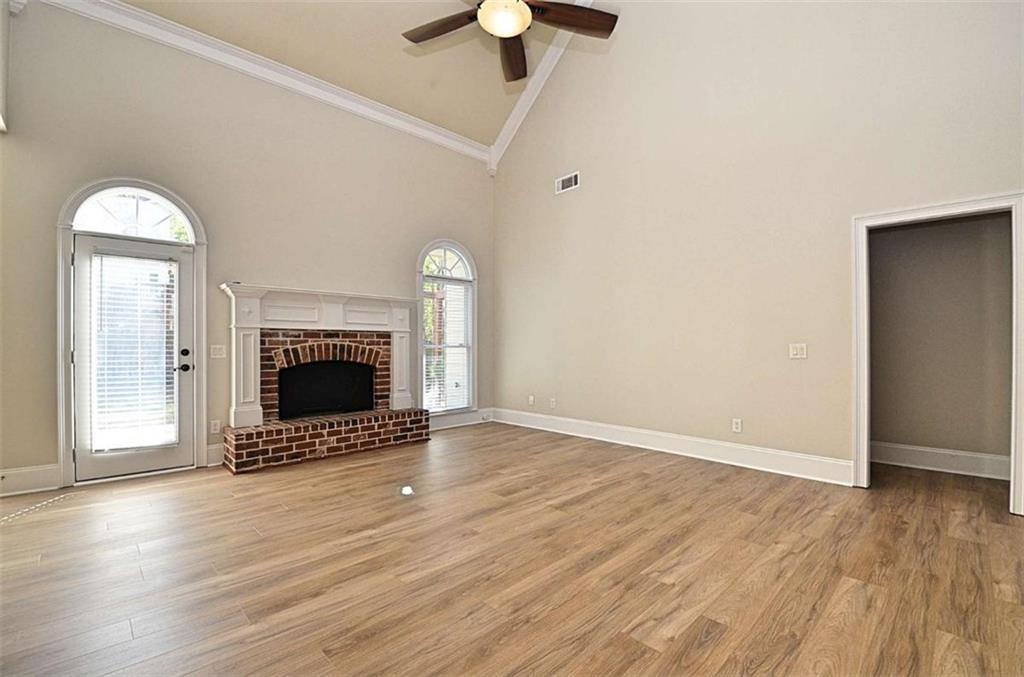101 Whitegrass Way Grayson, GA 30017 - Photo 6 of 41 an empty room with wooden floor a fireplace and a chandelier