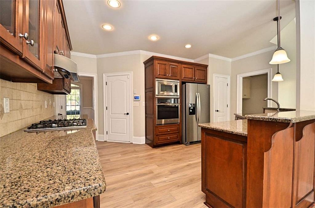 101 Whitegrass Way Grayson, GA 30017 - Photo 8 of 41 a kitchen with stainless steel appliances granite countertop a refrigerator a stove and a sink with wooden floor