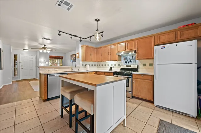 a kitchen with granite countertop a refrigerator a stove a sink and a dining table with wooden floor