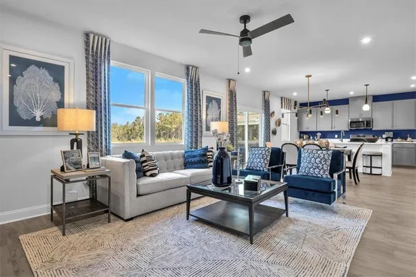 a living room with furniture kitchen view and a large window