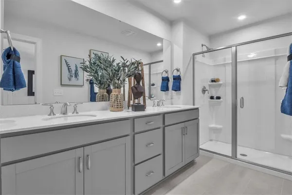 a spacious bathroom with a double vanity sink a mirror and a shower