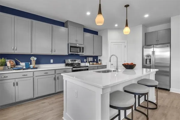 a kitchen with stainless steel appliances a sink a stove a refrigerator cabinets and dining table