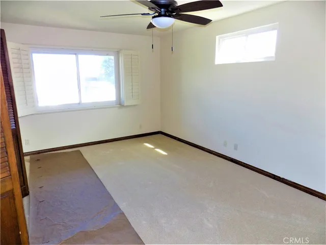 an empty room with a window and a fan
