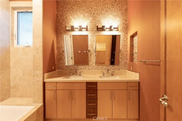 a bathroom with a double vanity sink a mirror and a bathtub