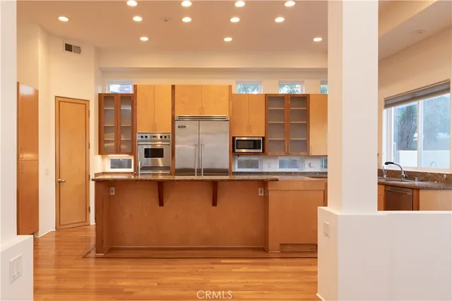 a large kitchen with stainless steel appliances a large counter top a stove and a refrigerator