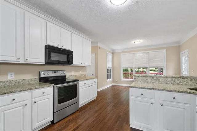 a kitchen with stainless steel appliances granite countertop a stove a sink and white cabinets