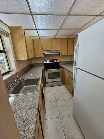 a kitchen with a sink a stove top oven and refrigerator