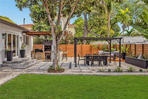 a view of a patio with a dining table and chairs with a large tree