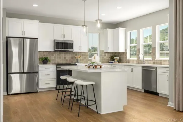 a kitchen with a refrigerator a stove a sink and white cabinets with wooden floor