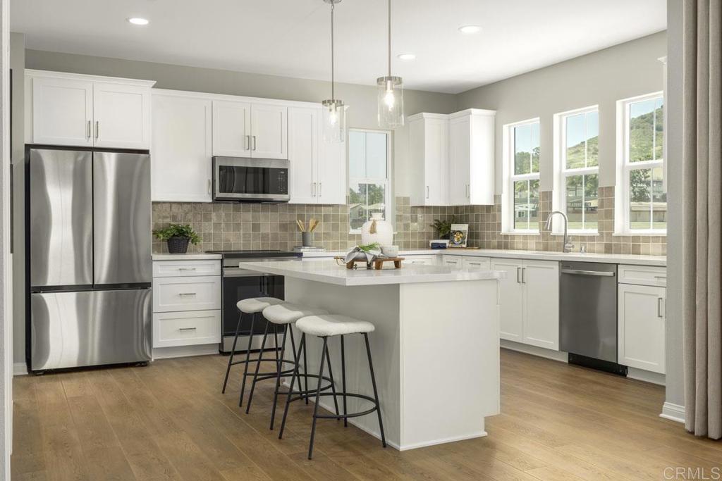 8600 Amherst Street Santee, CA 92071 - Photo 2 of 5 a kitchen with a refrigerator a stove a sink and white cabinets with wooden floor