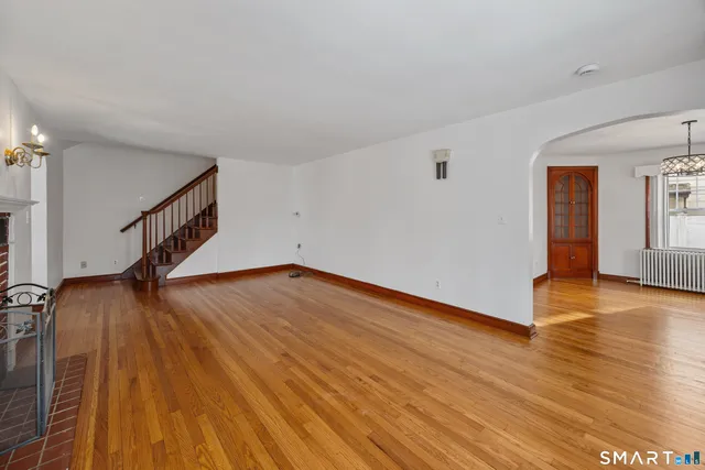 a view of an empty room with wooden floor and stairs