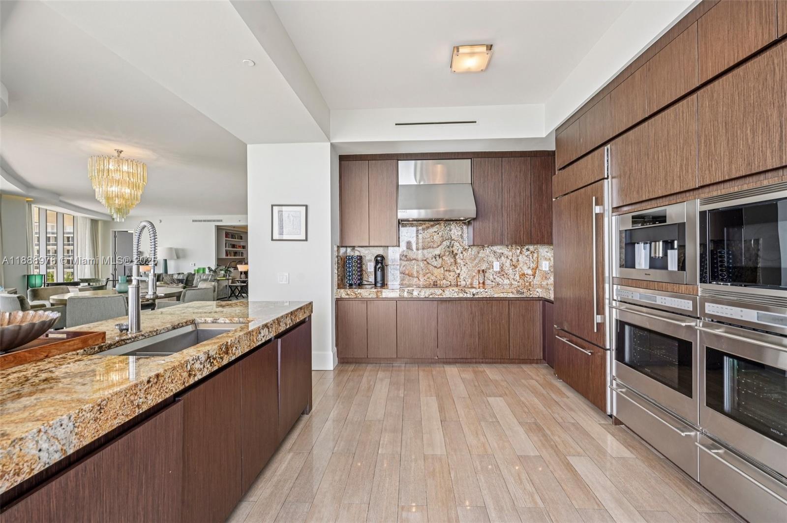9703 Collins Avenue, Unit 600 Bal Harbour, FL 33154 - Photo 16 of 53 a large kitchen with stainless steel appliances kitchen island granite countertop a large counter top and wooden floors