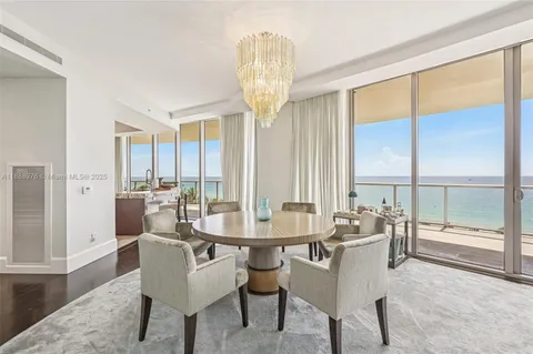 a dining room with furniture large windows and a chandelier