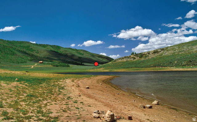 33 North Dry Valley Road, Unit 33 Helper, UT 84526 - Photo 4 of 8 Lakefront property featuring a natural shoreline, rolling green hills, a distant building, and a clear blue sky
