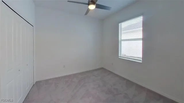 an empty room with a window and a fan