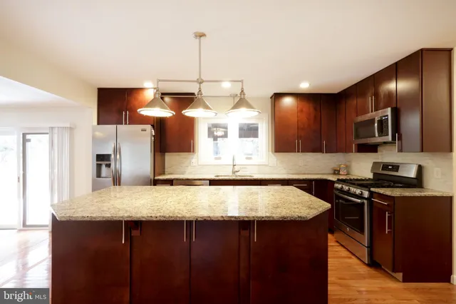 a kitchen with stainless steel appliances granite countertop a sink a microwave a stove and refrigerator