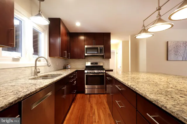 a kitchen with stainless steel appliances granite countertop a sink stove and refrigerator