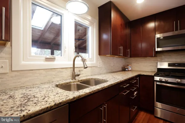 a kitchen with stainless steel appliances granite countertop a sink stove and cabinets