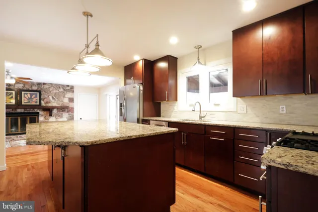 a kitchen with stainless steel appliances granite countertop a sink a stove and a wooden cabinets