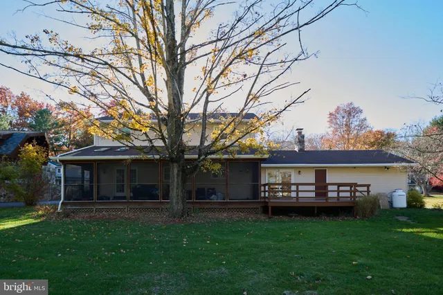 a view of house with a big yard and large trees