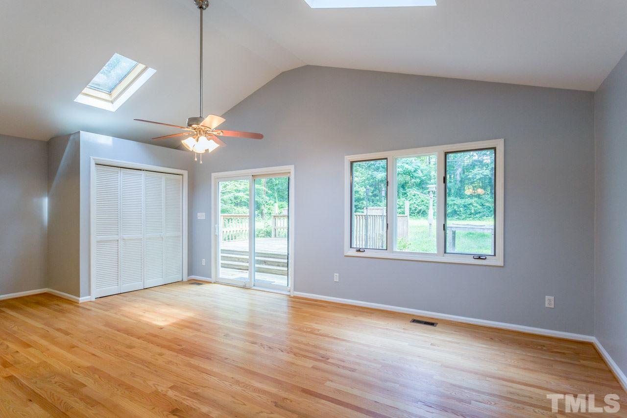 1547 Fountain Ridge Road Chapel Hill, NC 27517 - Photo 5 of 22 an empty room with wooden floor chandelier fan and windows