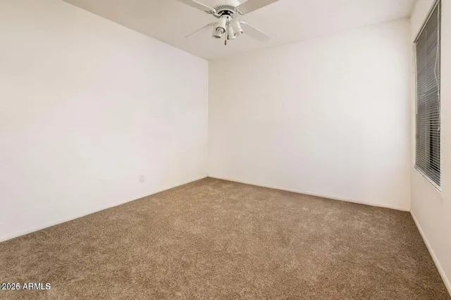 an empty room with a ceiling fan and a window