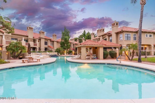 a view of a swimming pool with a table and chairs under an umbrella