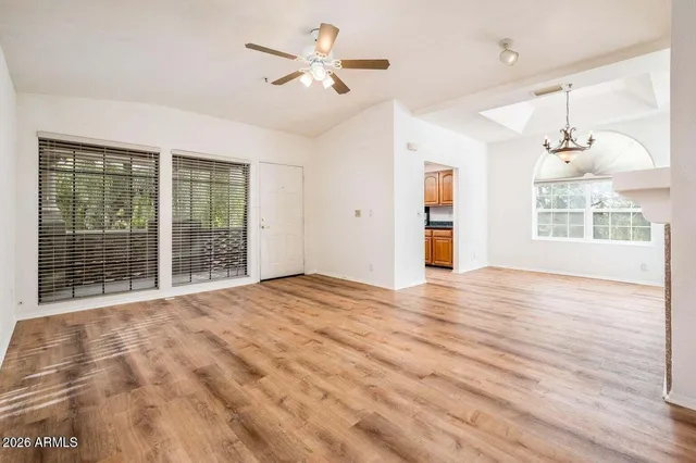 a view of an empty room with a window and wooden floor