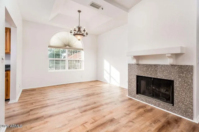 a view of an empty room with wooden floor fireplace and a window